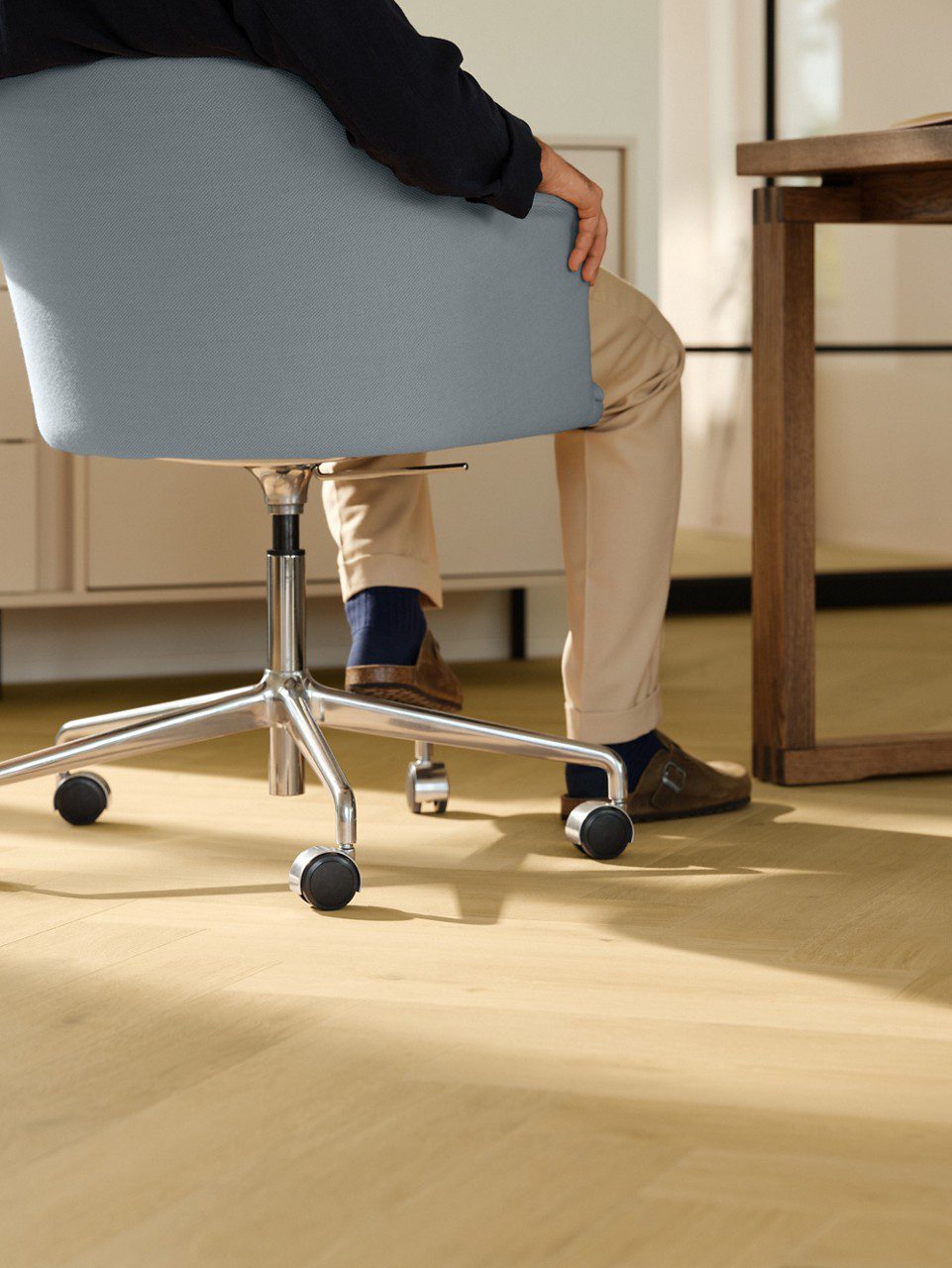 Laminat Quick Step Impressive Дизайн Nutmeg Oak, verlegt im Büro, blauer Bürostuhl mit sitzendem Mann