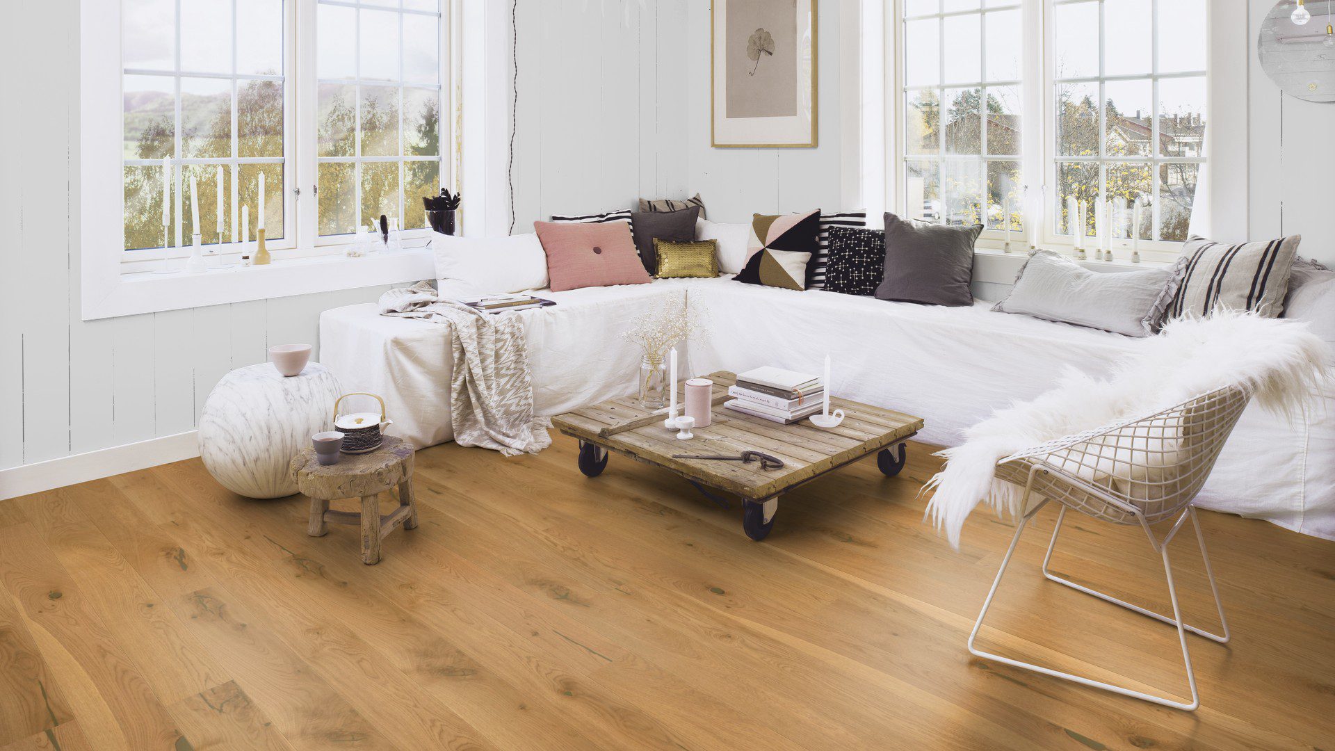 Naturaalparkett Bauwerk Casapark Budget Cut tamm 56 faasitud 2k, harjatud 138mm paigaldatud elutoa põrandale. Suur valge nurgadiivan koos diivanilauaga.