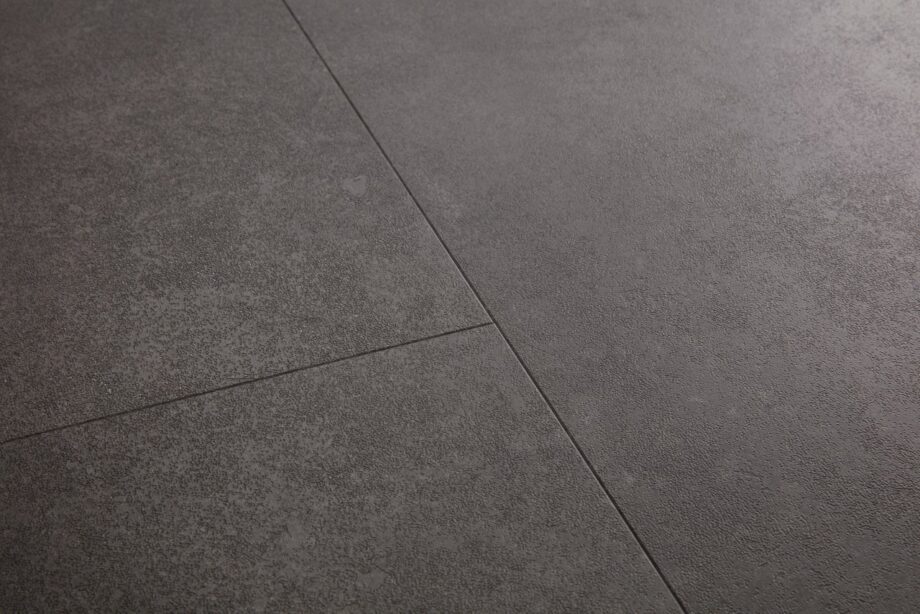 Vinyylilaatta Quick Step Oro Volcanic Rock asennettu lattialle tumma grafiitinharmaa vulkaaninen kivisävy moderni kivikuosi hienovarainen kivipinnan struktuuri ja luonnollinen sävyvaihtelu kestävä ja helppohoitoinen vinyylilattia sisustuksessa