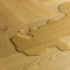 Laminaatparkett kalasaba Quick-Step Impressive Дизайн Cumin Oak naturaalne toon ja sorteering. Veelomp laminaadil viitamaks selle veekindlusele.