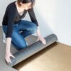 Woman is rolling the Quick-Step SilentWalk parquet and laminate floor underlay roll open on the underfloor
