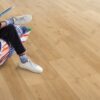 klick-vinylboden-quick-step-bloom-elegant-oak-natural Klick Vinylboden Quick Step Bloom Elegant Oak Natural im Wohnzimmer verlegt, ein Mann sitzt in einem Sessel.