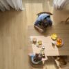 lvt-parkett-quick-step-bloom-brushed-oak-beige LVT parkett Quick Step Bloom Brushed Oak Beige paigaldatud söögitoa põrandale, söögilaud ja toolid, pere einestamas laua taga.