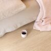 LVT põrandakate Quick-Step Bloom Pure Oak Blush paigaldatud magamistoa põrandale. voodi ja kohvitass põrandal