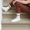 vinuulparkett-quick-step-blos-chia-tamm Vinüülparkett Quick-Step Blos Chia tamm helehalli tooniga paigaldatud koridori põrandale ja trepile. Mees istub trepil ja vaatab telefoni.