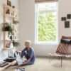 LVT Quick-Step Illume Sandstone concrete betooni disainiga paigaldatud elutoa põrandale. Naisterahvas paneb vinüülplaati vinüülplaadi mämgijasse.